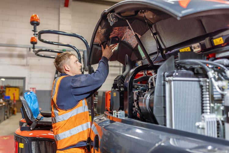 a service engineer putting a light in the engine cover of a kubota excavator