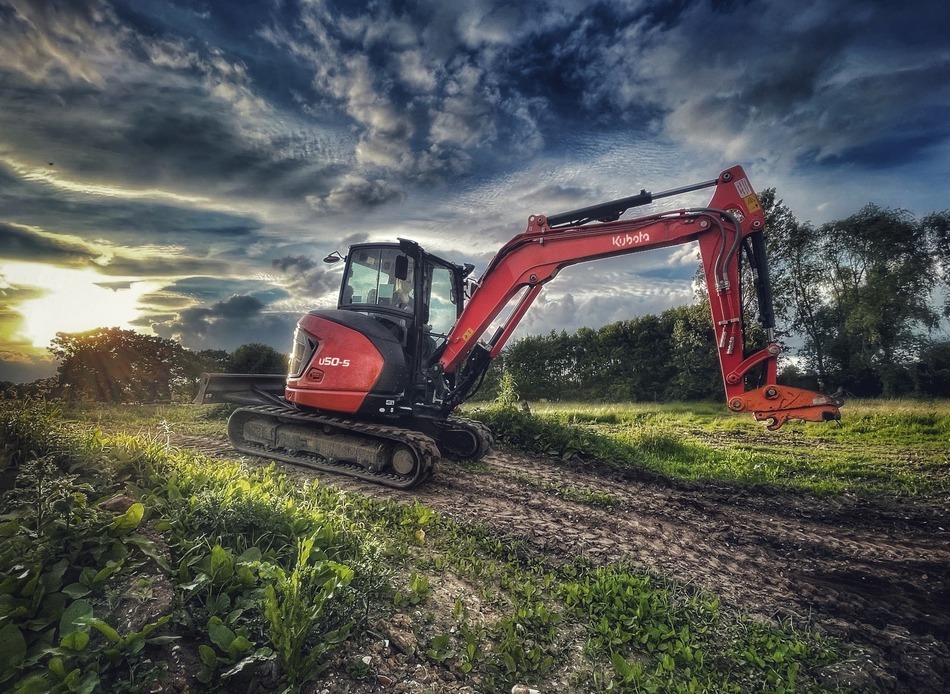Kubota U50-5 excavator with a moody sky tracking through a field Kubota U50-5 excavator with a moody sky tracking through a field