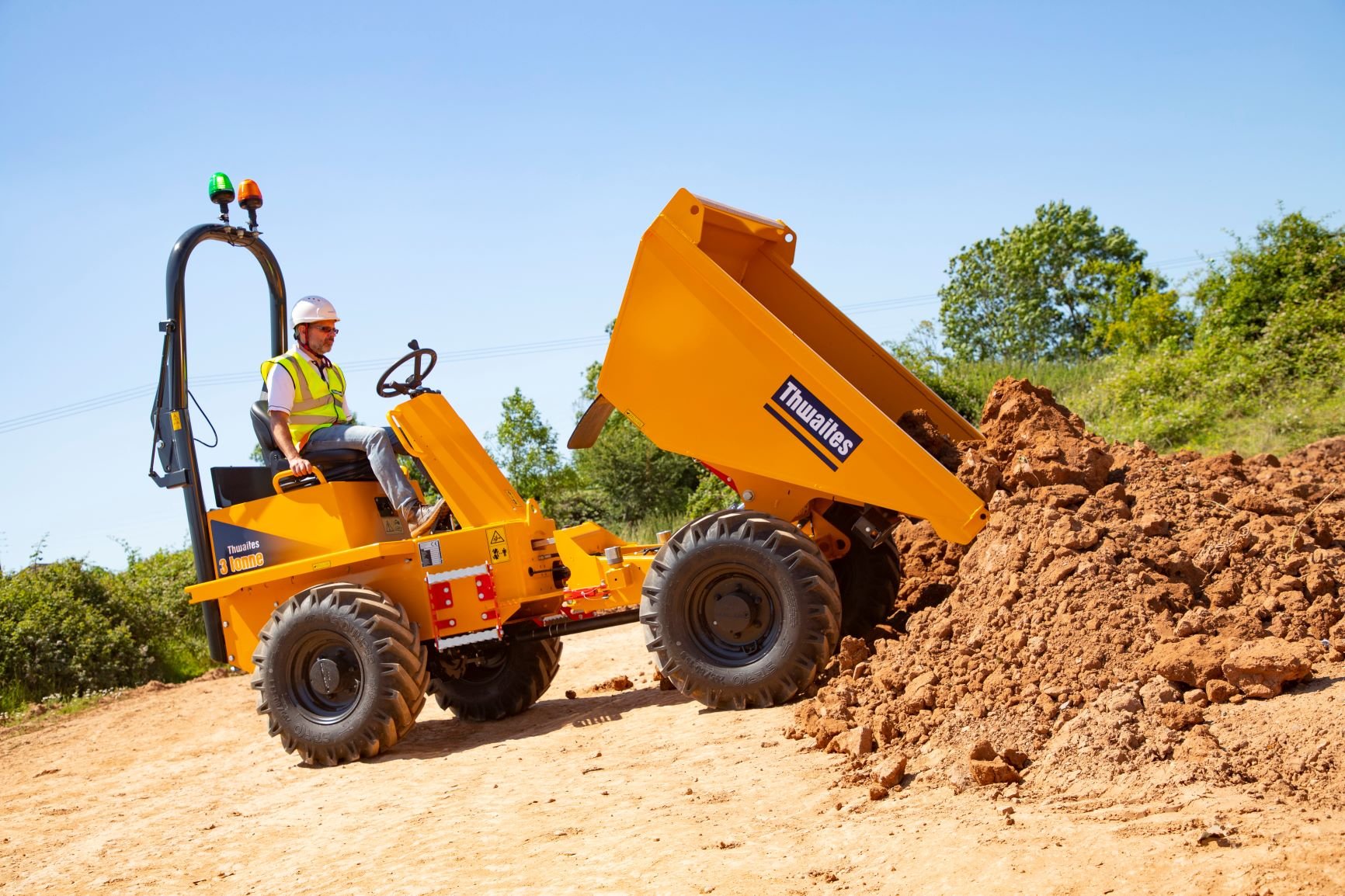 Thwaites 3 tonne front tip dumper, unloading the skip onto the ground. Part filled with soil