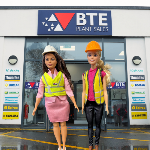 BuildHER Barbie campaign photo of business Barbie and Construction Barbie standing in front of BTE Plant Sales office