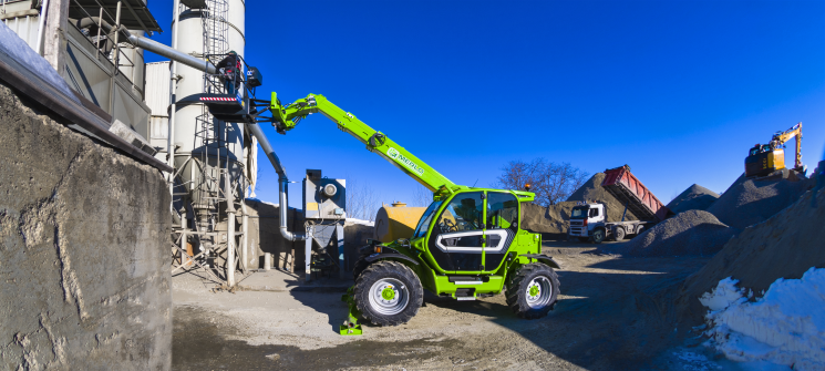 Merlo P35.11 stabilised telehandler with man basket attached. Working on site with a man in the basket fixing some pipe work