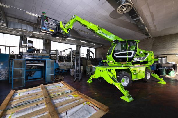 Merlo ROTO40.18 S rotating telehandler, working inside with a man basket attached. A lady is attaching lighting to the ceiling
