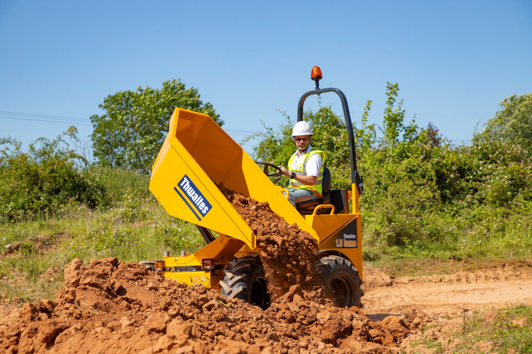 Thwaites 1.5 Tonne Power Swivel, with a male operator, skip turned to the right and emptying out mud.