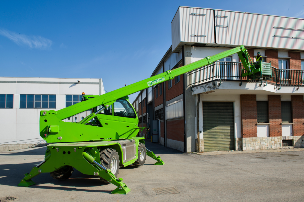 Merlo ROTO40.16 S rotating telehandler on site with front and back stabilisers down and a man basket attached to the extended boom